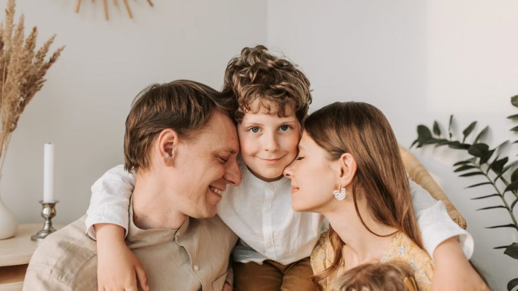 A joyful family moment with parents and their son embracing indoors.